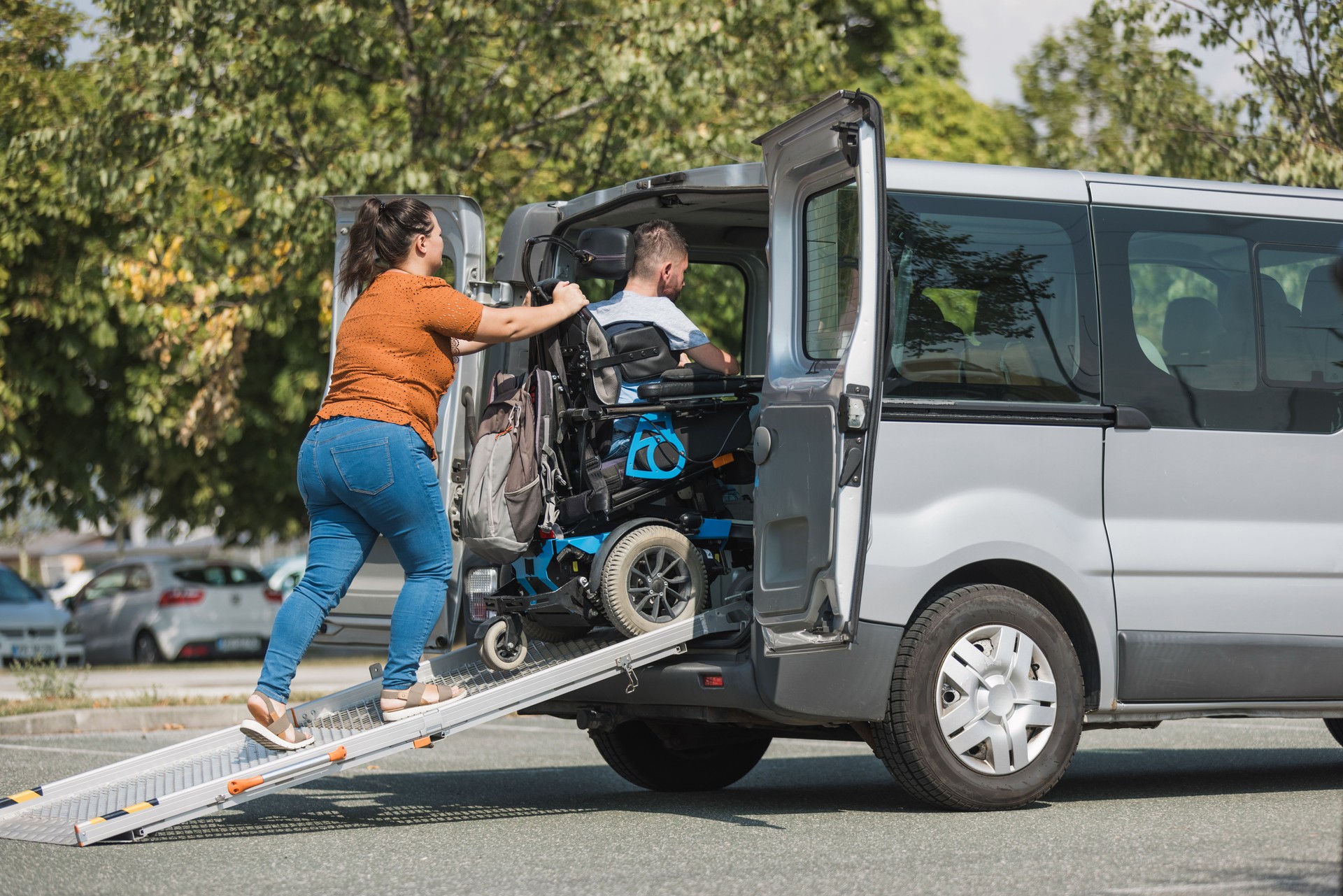 Man with a disability getting into an accessible vehicle with help