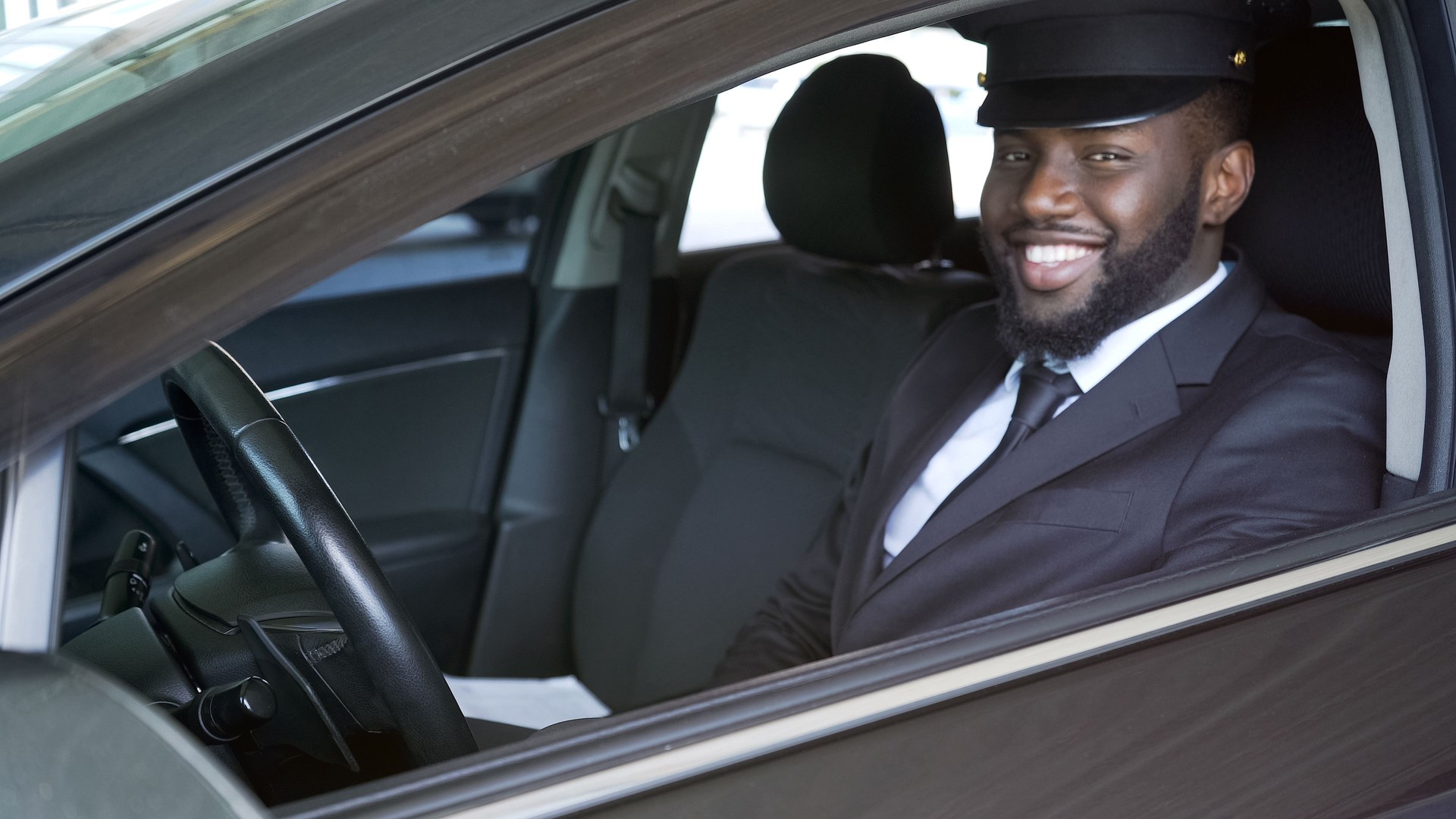 Happy African American chauffeur looking into camera, luxury transfer, service