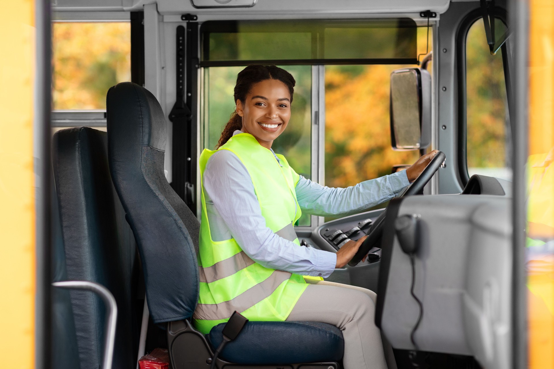 Happy black female driver sitting in bus and looking at camera